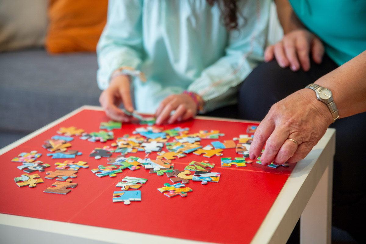 kid and adult assembling a puzzle together