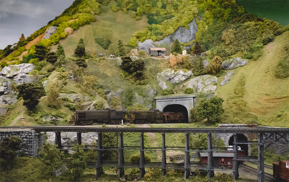 A picture of a model train going into a tunnel.