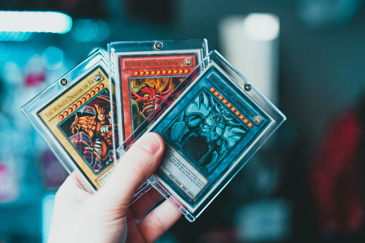 person holding three yugioh cards