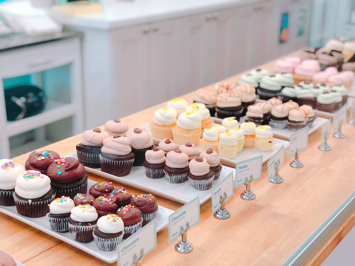 Platters of baked cupcakes lined up on a table